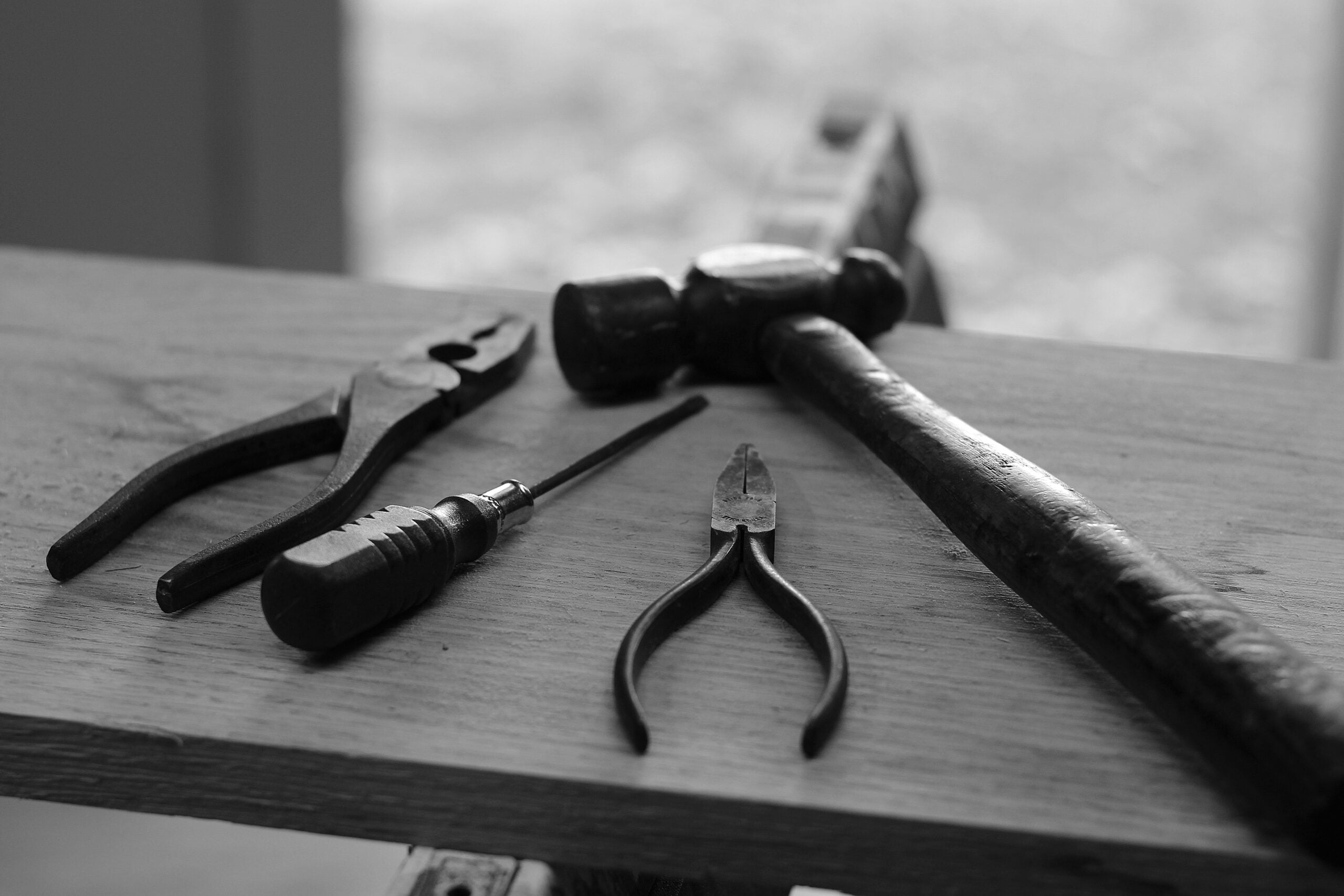 A hammer, pliers and other tools on a piece of wood